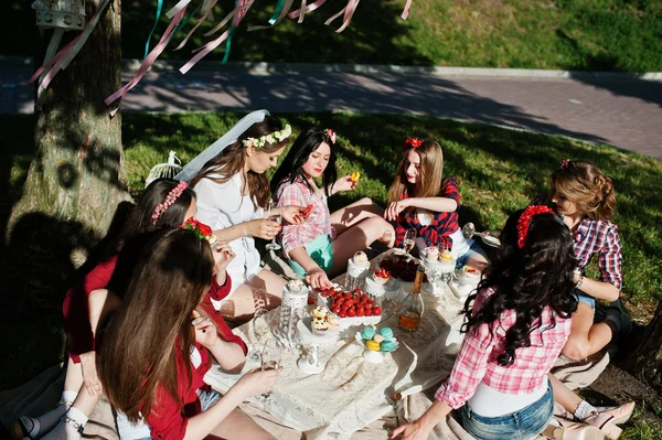 Siete chicas felices y sexy sentado en la mesa de picnic y comer st — Foto de Stock