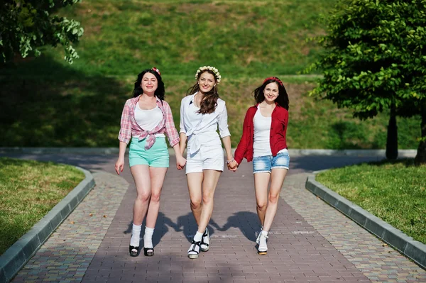 Tres niñas felices en pantalones cortos y guirnaldas en la cabeza caminando d — Foto de Stock