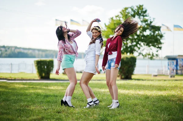 Tres chicas felices en pantalones cortos y guirnaldas en cabezas bailando un — Foto de Stock