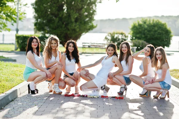 Seven happy and sexy girls on short shorts sat at sunset park on — Stock Photo, Image