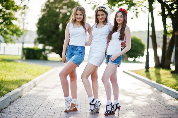 Drei glückliche und sexy Mädchen in kurzen Shorts und weißen Hemden posieren — Stockfoto