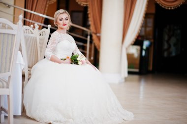 Muhteşem sarışın gelin el altında oturan gr düğün buketi ile