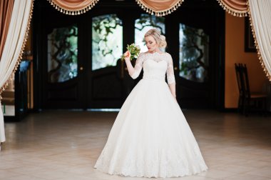 Muhteşem sarışın gelin kapalı büyük düğün salonu arka plan poz verdi.