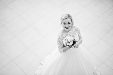 Muhteşem sarışın gelin kapalı büyük düğün salonu poz verdi. Siyah ve