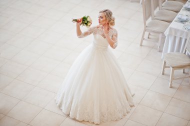 Muhteşem sarışın gelin kapalı büyük düğün salonu poz verdi.