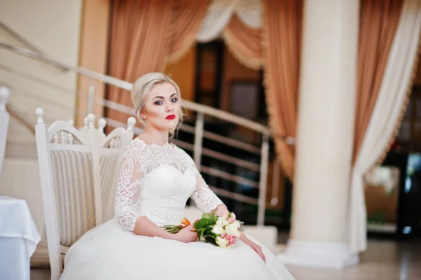 Prachtige blonde bruid met bruiloft boeket dichtbije zit op gr — Stockfoto
