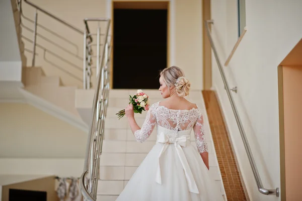 Hermosa novia rubia posó en las escaleras gran salón de bodas interior — Foto de Stock