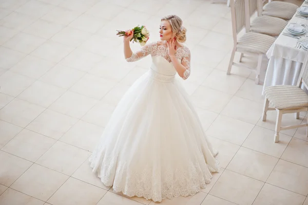 Prachtige blonde bruid gesteld binnen grote Bruiloftszaal — Stockfoto