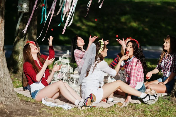 Счастливые и сексуальные девушки сидят за столом для пикника и едят клубнику — стоковое фото