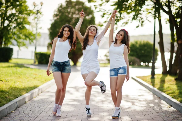 Tre glada och sexiga tjejer på korta shorts och vita skjortor pose — Stockfoto
