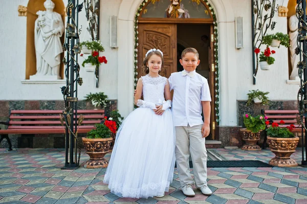 Πρώτη θεία κοινωνία, τον αδελφό και αδελφή μείνετε στο λευκό φόρεμα bac — Φωτογραφία Αρχείου