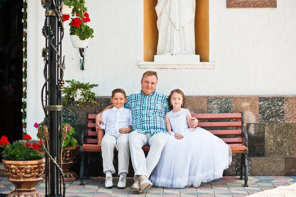Op de eerste heilige communie zittend op de Bank achtergrond en gelukkige familie — Stockfoto
