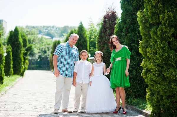 Glückliche Familie bleibt in der Thuja-Gasse und schaut in die Kamera — Stockfoto