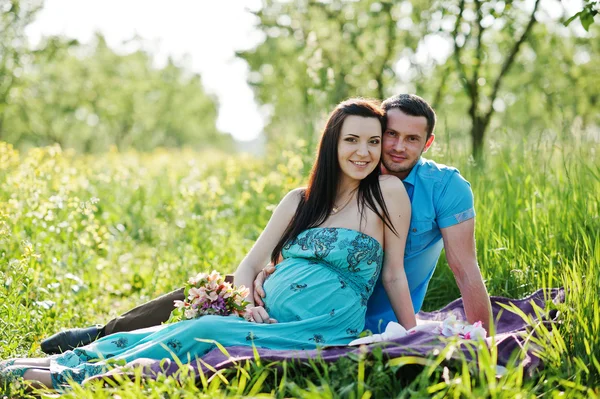 Feliz pareja embarazada en vestido turquesa en el jardín —  Fotos de Stock