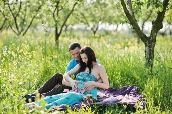 Feliz pareja embarazada en vestido turquesa en el jardín — Foto de Stock