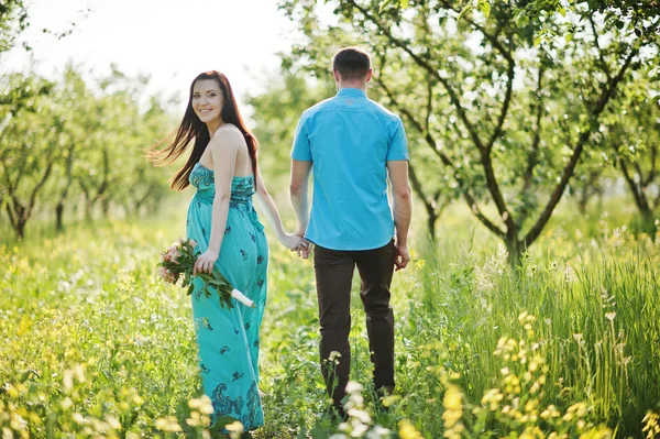 Feliz pareja embarazada en vestido turquesa en el jardín —  Fotos de Stock