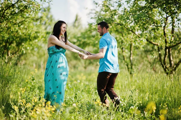 Happy pregnant couple at turquoise dress on the garden — Stock Photo, Image