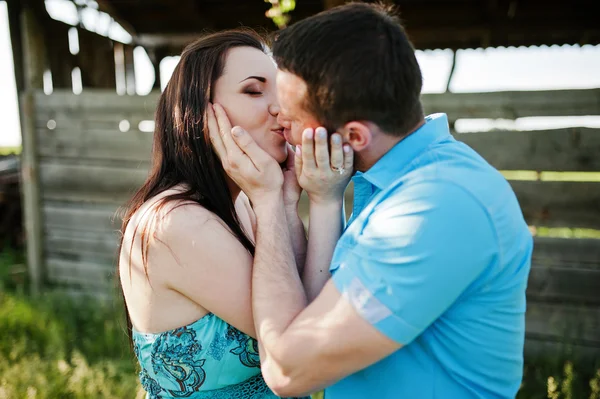 Happy pregnant couple at turquoise dress kissing on the garden — Stock Photo, Image