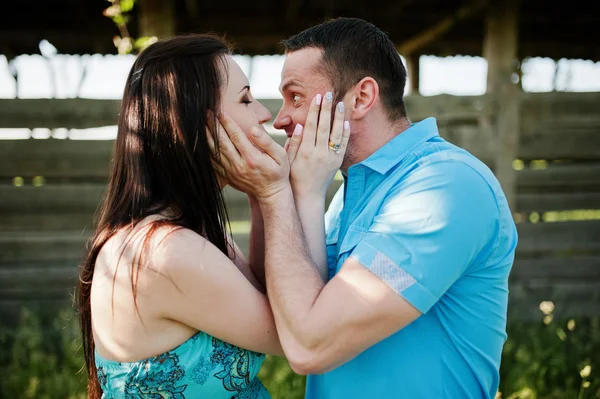 Feliz casal grávida no vestido turquesa beijando no jardim — Fotografia de Stock