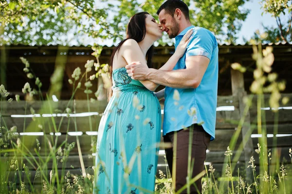 Feliz pareja embarazada en vestido turquesa en el jardín —  Fotos de Stock