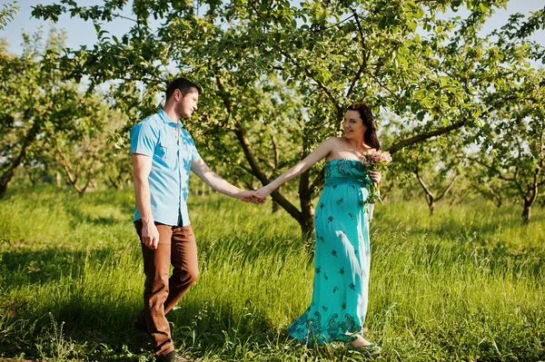 庭の青緑色のドレスで幸せな妊娠カップル — ストック写真
