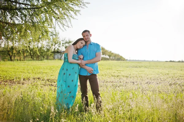 Joyeux couple enceinte à robe turquoise sur le jardin — Photo