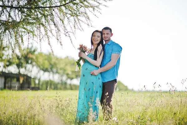 Glückliches schwangeres Paar im türkisfarbenen Kleid im Garten — Stockfoto