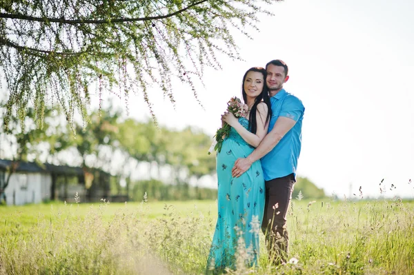 Feliz pareja embarazada en vestido turquesa en el jardín — Foto de Stock