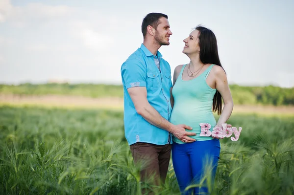 Happy pregnant couple on wreath field in love — Stock Photo, Image