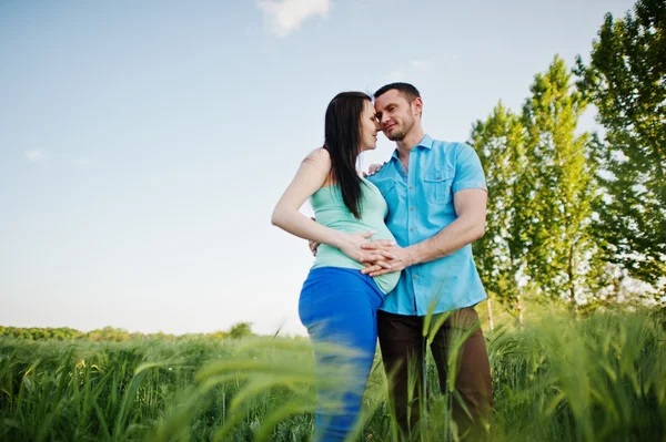 Happy pregnant couple on wreath field in love — Stock Photo, Image