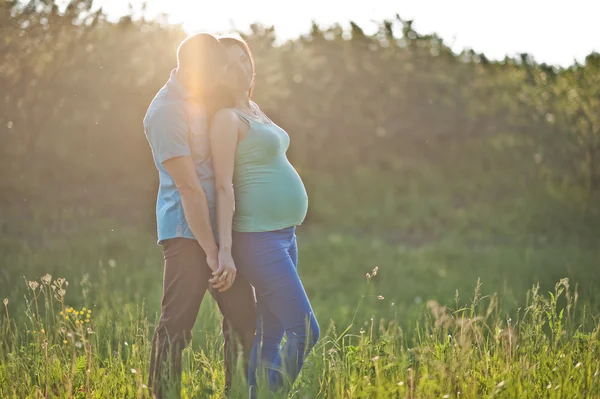 Joyeux couple enceinte au jardin sur le coucher de soleil magique — Photo