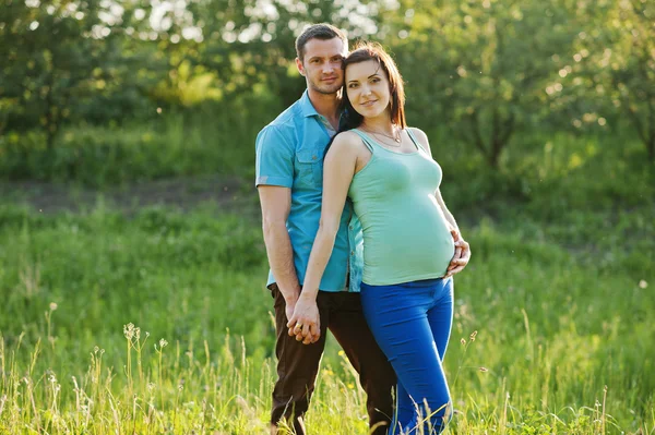 Gelukkige zwangere paar op tuin op statige zonsondergang — Stockfoto