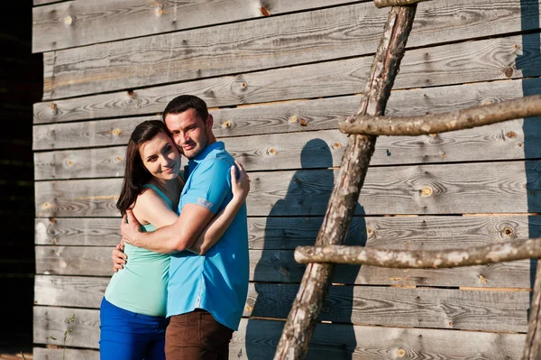 Šťastný pár těhotná pozadí dřevěná stodola při západu slunce — Stock fotografie