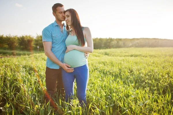 Bahçe magestic günbatımı üzerinde mutlu hamile çifte — Stok fotoğraf