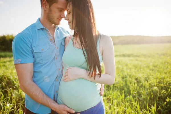 Happy pregnant couple at garden on magestic sunset