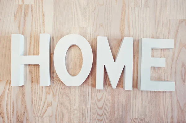 Witte houten letters Home bij lichte houten achtergrond — Stockfoto