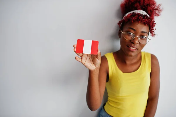 African american woman with afro hair, wear yellow singlet and eyeglasses, hold Peru flag isolated on white background.