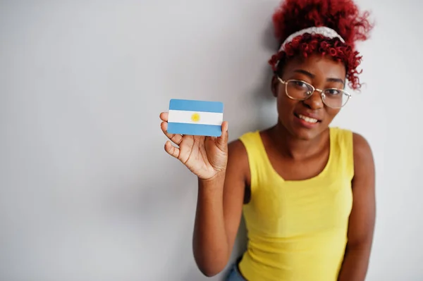 African american woman with afro hair, wear yellow singlet and eyeglasses, hold Argentina flag isolated on white background.