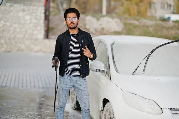 South asian man or indian male washing his white transportation on car wash.