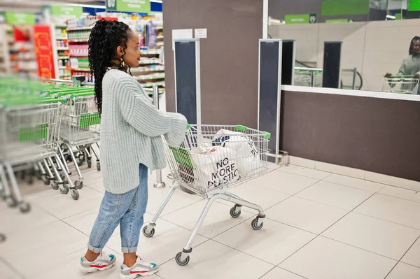 African woman with shopping cart trolley posed indoor market.