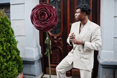 Bej rengi eski okul takım elbiseli şık bir afro adam. Üstü başı çıplak, şık, genç Afrikalı bir erkek..