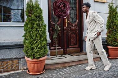 Bej rengi eski okul takım elbiseli şık bir afro adam. Üstü başı çıplak, şık, genç Afrikalı bir erkek..