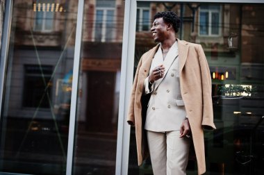 Bej rengi eski okul takımı ve ceketli şık bir afro adam. Üstü başı çıplak, şık, genç Afrikalı bir erkek..