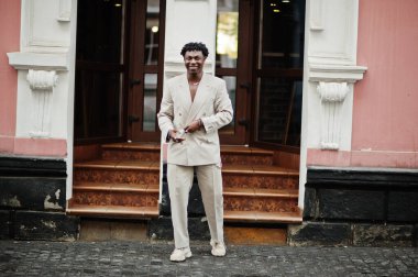 Bej rengi eski okul takım elbiseli şık bir afro adam. Üstü başı çıplak, şık, genç Afrikalı bir erkek..