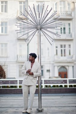 Bej rengi eski okul takım elbiseli şık bir afro adam. Üstü başı çıplak, şık, genç Afrikalı bir erkek..