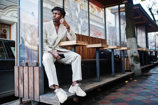 ベージュの古い学校のスーツのスタイリッシュなアフロ男が路上のテーブルに座っています ファッショナブルな若いですアフリカの男性でカジュアルジャケットオン裸胴 — ストック写真