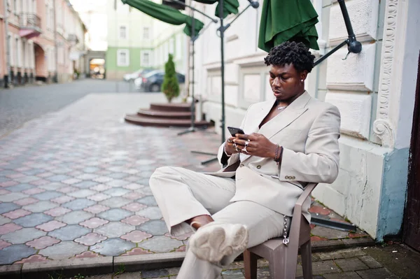 Stílusos Afro Férfi Bézs Régimódi Öltönyben Kint Egy Székben Mobiltelefonnal — Stock Fotó