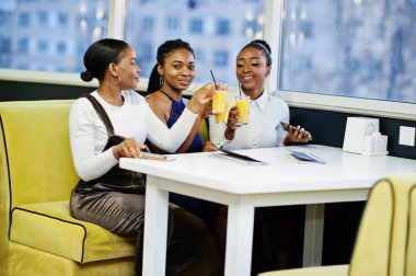 Restoranda poz veren, meyve suyu içen üç Afrikalı kadın..