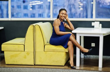 Lokantada poz veren mavi elbiseli Afro-Amerikan kadın..