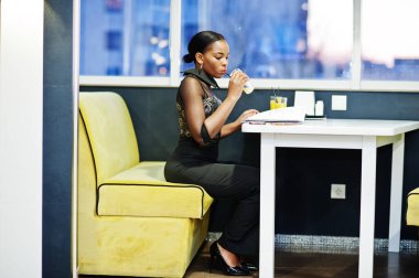 Çekici Afrikalı Amerikalı kadın restoranda poz veriyor ve meyve suyu içiyor..